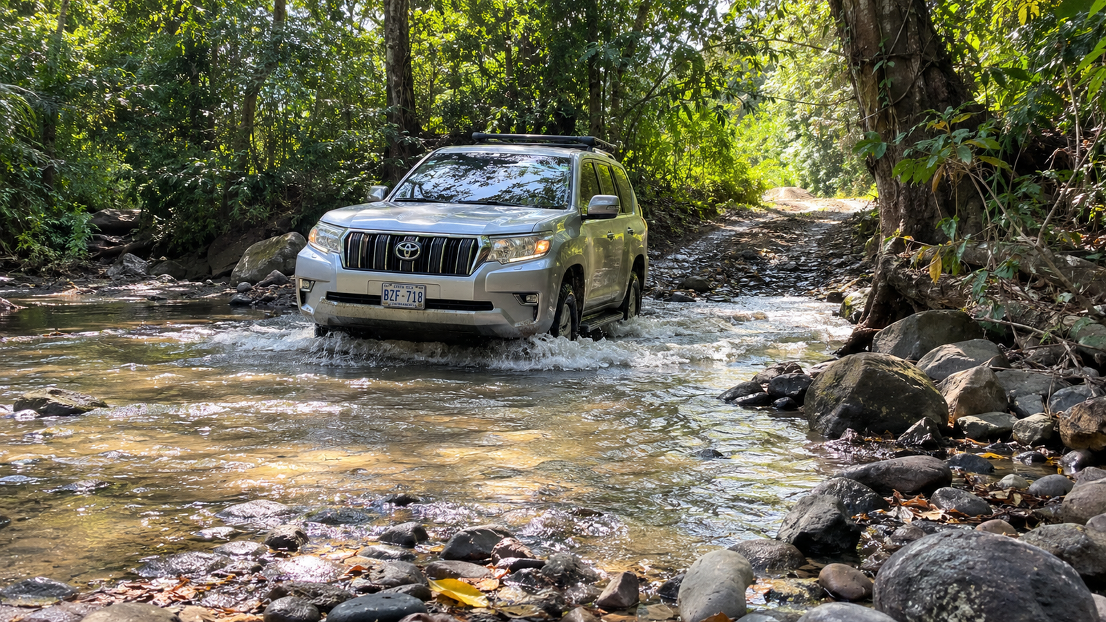 Silver 4x4 SUV crossing the shallow river ford on the Monkey Trail Route 911 between Sardinal and Potrero in Guanacaste Costa Rica